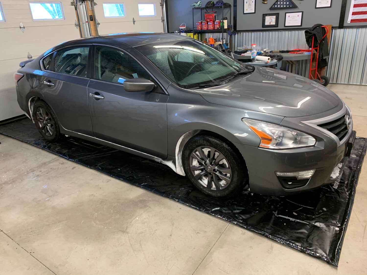 Sedan on black containment mat in garage.